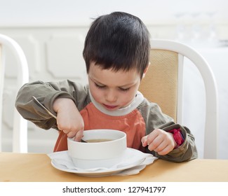 Small Child Boy Eating A Soup In A Restaurant.