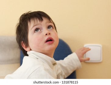 A Small Child, Boy Or Girl, Looking Up And Reaching To A Light Switch.