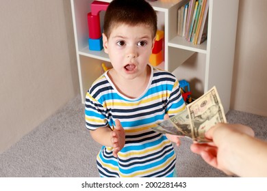 A Small Child Boy Takes Dollar Bills From The Hands Of An Adult Parent. Financial Literacy In Children And Pocket Money.