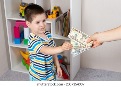 A Small Child Boy Takes Dollar Bills From The Hands Of An Adult Parent. Financial Literacy In Children And Pocket Money