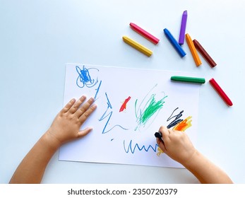 small child draws with pastel crayons on white table. - Powered by Shutterstock