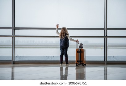 Small Child Flying To The Destination. She Is Saying Goodbye To The Departing Aircraft. Copy Space In Left Side