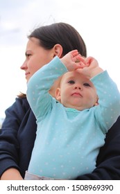 Small Child In Her Mother's Arms, Shot From Below