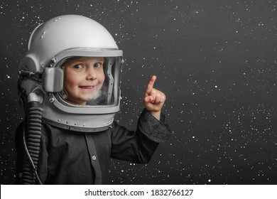 A small child imagines himself to be an astronaut in an astronaut's helmet. 