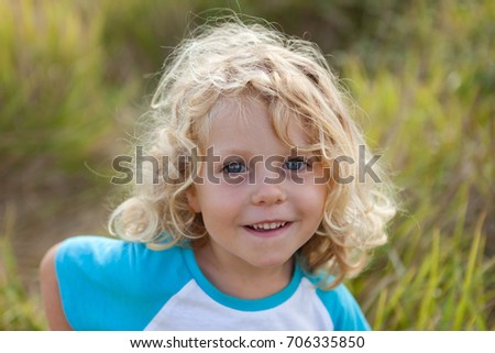 Small child with long blond hair enjoying of a sunny day