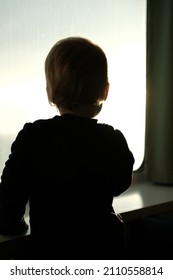 Small Child Looking Out Of The Window.