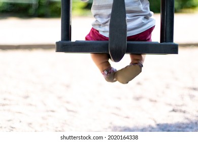 Small Child On A Black Baby Swing On A Playground