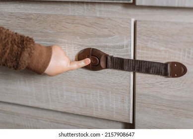 A Small Child Opens A Chest Of Drawers Wardrobe With Child Protection. Dangerous Situation At Home. Child Trapped Finger In The Door.