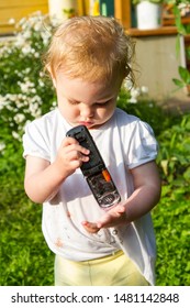 Small Child Is Playing With A Broken Mobile Phone