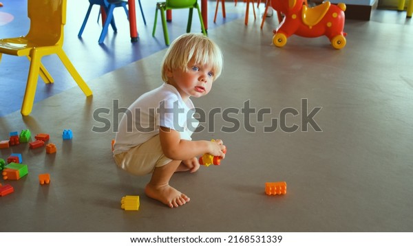 a small child plays with a construction set and a\
toy car on the floor