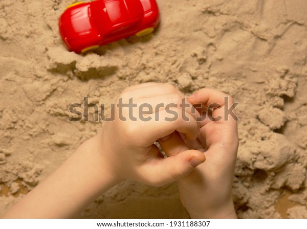 small Child plays\
with kinetic sand and toys. Sensory experiences of the child, happy\
childhood. copy space.