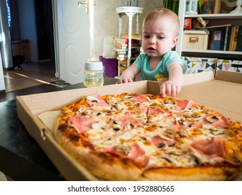 A Small Child Reaches For A Slice Of Pizza