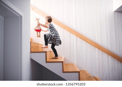 A Small Child With A Soft Toy Walking Up The Stairs.