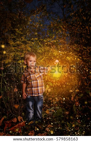 small child standing in the snow holding a candle lit lantern in the coastal forest.