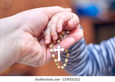 A small child takes a rosary from his dad's hand - Shutterstock ID 1339331312