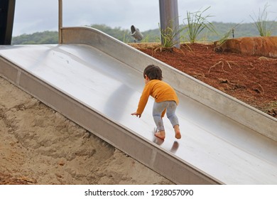 Small Child Walking Up A Slippery Dip