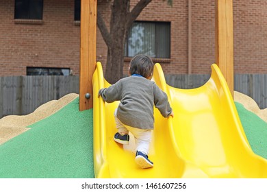 Small Child Walking Up A Yellow Slippery Dip