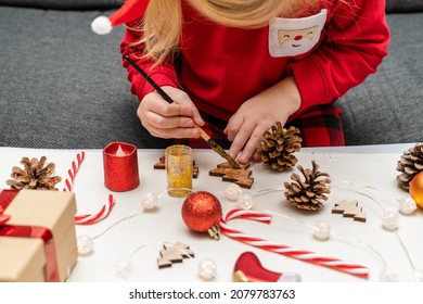 Small child wearing Christmas holiday pajamas, doing crafts, painting Christmas tree decorations, sitting at table. DIY and handmade concept. - Powered by Shutterstock