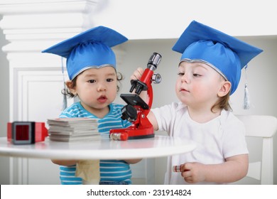 Small Children In Blue Graduation Hat Adjust Microscope On Table