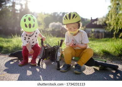 Small Children With Face Masks Playing Outdoors With Bike, Coronavirus Concept.