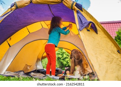 Small Children, Kids Play,read Book In Orange Tourist Tent. Family Trip, Hike To Nature. Backyard Games, Having Fun. Outdoor Recreation, Activity. Self-assembly, Setting Up Camping Tent On Lawn,grass.