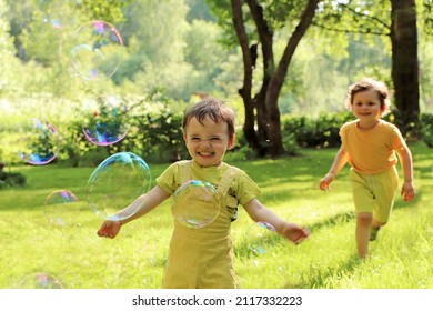 Small Children Play With Soap Bubbles In The Summer Outdoors.