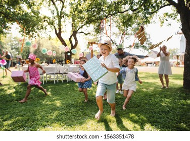 Small children ruunning with present outdoors in garden on birthday party. - Powered by Shutterstock