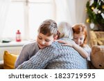 Small children with senior grandfather indoors at home at Christmas, hugging.