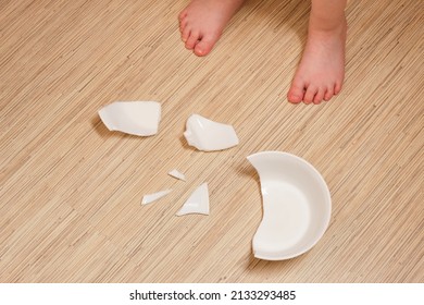small childs legs and fragments of broken dishes. the child broke the dishes, dangerous fragments, the child cut himself with a fragment