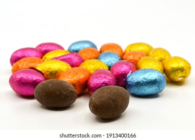 Small Chocolate Eggs In Coloured Foil Wrappings On A Plain Background. No People.