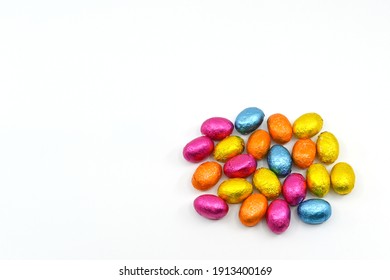 Small Chocolate Eggs In Coloured Foil Wrappings On A Plain Background. No People.