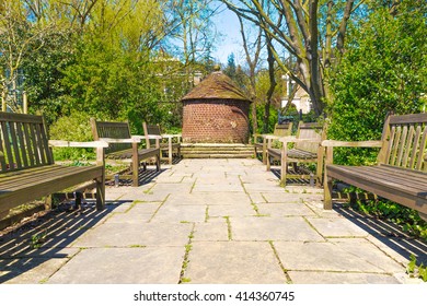 A Small Circular Red Brick Hut And Wooden Benches In The Sun At The New River Walk, Canonbury, London