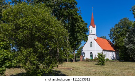 In a small city of Latvia, a white church with a red roof and a tower can be seen between the trees on a sunny summer day. Lutheran Church.
 - Shutterstock ID 1111053812