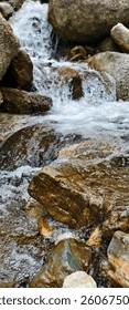 A small, clear river flows in the middle of a sizable expanse of rocks. 