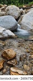 A small, clear river flows in the middle of a sizable expanse of rocks. 