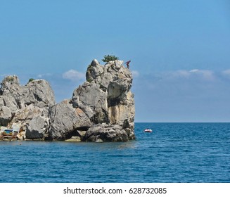 Small Cliff Above The Sea. Man Jumping From A Cliff
