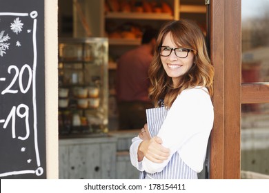Small Coffee Shop Owner Standing In Front Of Store.