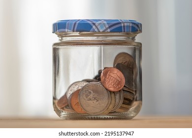 Small Coins Of American Cents In A Closed-lid Jar On A Neutral Background, Close-up, Selective Focus. A Concept For Business And Finance, Savings And Price Increases.
