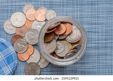 Small Coins Of American Cents In A Jar With An Open Lid On A Blue Textured Background. A Concept For Business And Finance, Savings And Price Increases.