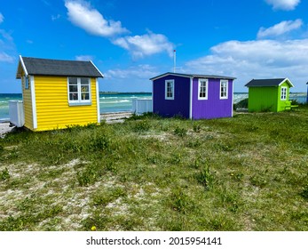 Small colorful houses under the sun at the beach on the island of Aero in Denmark during a summer vacation