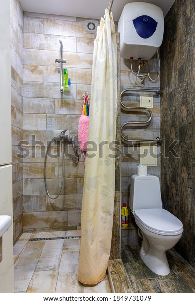 Small compact bathroom divided with shower curtain\
and toilet