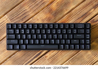 Small compact black gaming computer keyboard on a table made of wooden pine boards. Wireless keyboard with mechanical switches for gadgets and computer. Copy space. Close-up - Shutterstock ID 2214376699