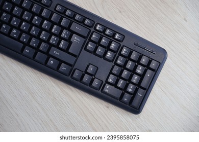 Small compact black gaming computer keyboard on a table made of wooden pine boards. Wireless keyboard with mechanical switches for gadgets and computer. Copy space