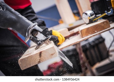 Small Construction Project. Men Cutting Piece of Wood Board Using Reciprocating Saw. Construction Site Power Equipment. - Shutterstock ID 1384936424