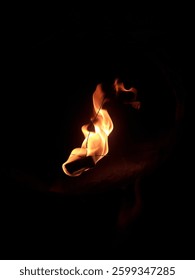 A small controlled flame burning in darkness, creating a warm glow.