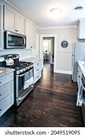 A Small Cottage Kitchen With Gray Cabinets And Dark Hardwood Floors In A Short-term Rental House.