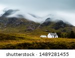 A small cottage under a mountain in mist