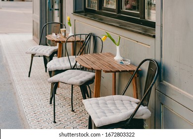 Small Cozy Chairs With Sit Pillows And Table Stands Near The Restaurant On The Street. Coffee. Urban. Place. Outdoor. Exterior. Design. Business. Yellow Flowers On The Table. Business Idea