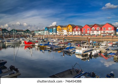 A small and cozy harbor in the town of Exmouth. There are many vessels moored here. Around the harbor are colorful beautiful houses. Devon. England