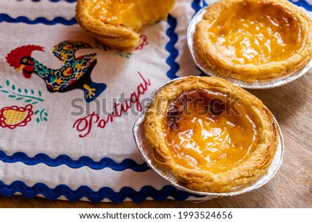 Small cream cakes, typical of Portugal, with some napkins with the Barcelos rooster and the letters of Portugal.